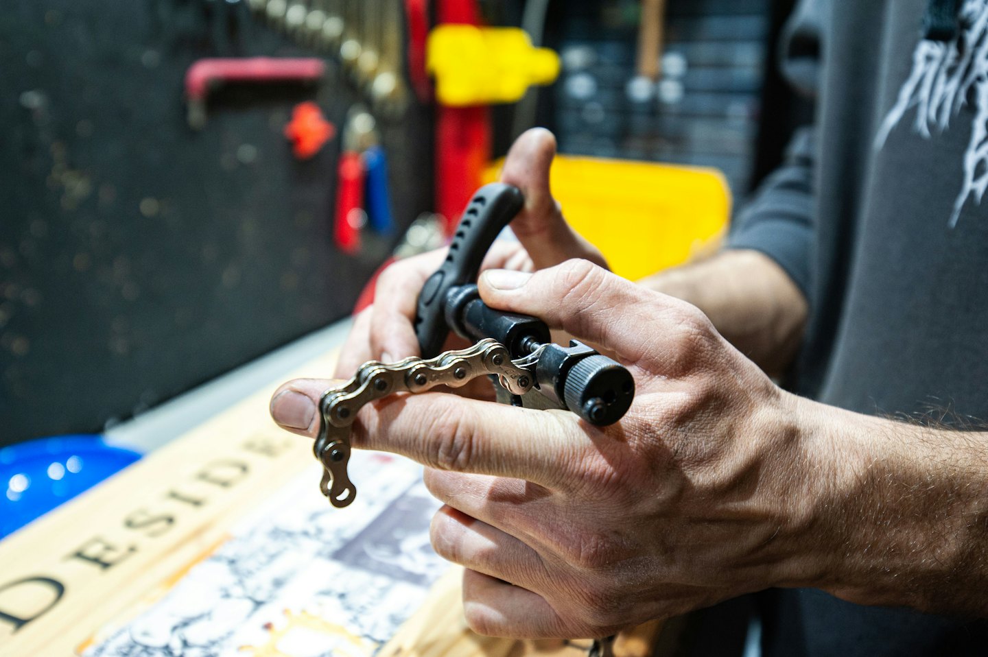 Händer som håller cykelkedja och verktyg för reparation.
